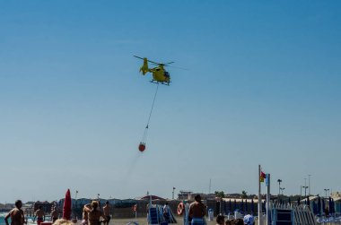 Roma, İtalya - Temmuz 2017: Yangın helikopteri tiren denize Ostia, İtalya yakın yangın söndürme için bir sepet içinde su alıyor