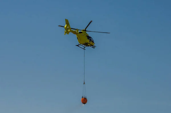 Roma, Włochy - lipca 2017: Helikopter strażacki jest podniesienie wody w koszyku do gaszenia pożaru na Morzu Tyrreńskim w pobliżu Ostia, Włochy — Zdjęcie stockowe