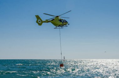Roma, İtalya - Temmuz 2017: Yangın helikopteri tiren denize Ostia, İtalya yakın yangın söndürme için bir sepet içinde su alıyor