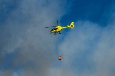 Roma, İtalya - Temmuz 2017: Yangın helikopteri tiren denize Ostia, İtalya yakın yangın söndürme için bir sepet içinde su alıyor