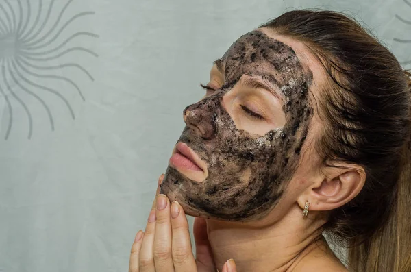 Молодая очаровательная девушка делает черный уголь маску на ее лице — стоковое фото