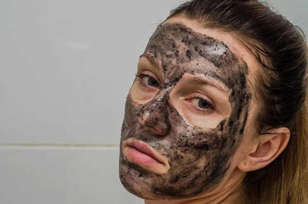 Młoda, urocza dziewczyna sprawia, że czarny węgiel maski na twarzy — Zdjęcie stockowe