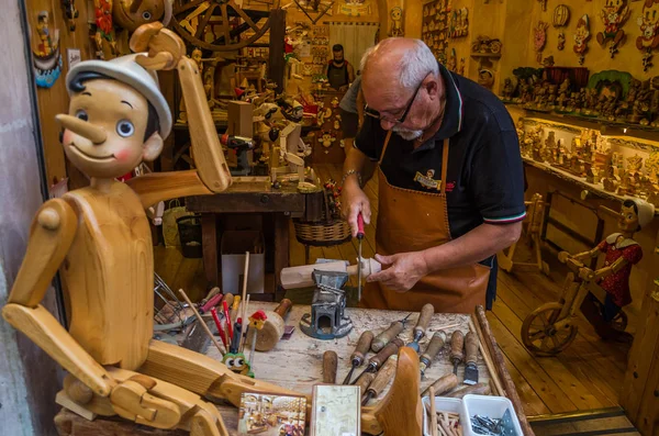 ROMA, ITALIA - JULIO 2017: Taller donde el maestro examina los juguetes tradicionales de madera hechos a mano de Pinocho —  Fotos de Stock