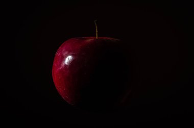 Düşük bir anahtar içinde siyah bir zemin üzerine izole Kırmızı elma
