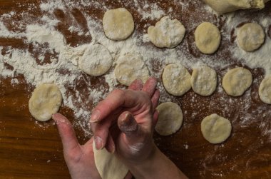 Bir kadın aşçı el un hamur bir tablo üzerinde pişmiş ve vareniki yapmak