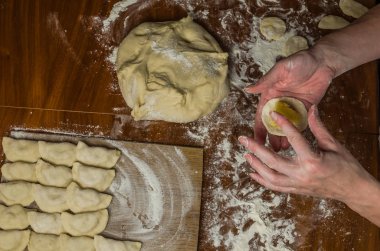 Bir kadın aşçı el un hamur bir tablo üzerinde pişmiş ve vareniki yapmak