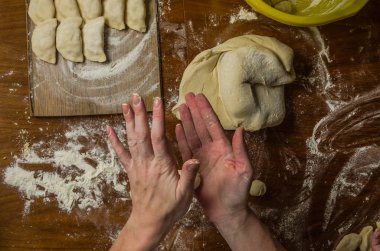 Bir kadın aşçı el un hamur bir tablo üzerinde pişmiş ve vareniki yapmak