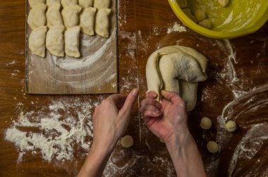 Bir kadın aşçı el un hamur bir tablo üzerinde pişmiş ve vareniki yapmak