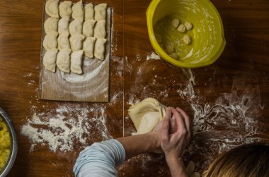 Bir kadın aşçı el un hamur bir tablo üzerinde pişmiş ve vareniki yapmak