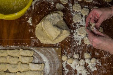 Bir kadın aşçı el un hamur bir tablo üzerinde pişmiş ve vareniki yapmak