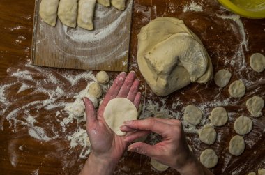 Bir kadın aşçı el un hamur bir tablo üzerinde pişmiş ve vareniki yapmak