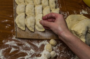 Bir kadın aşçı el un hamur bir tablo üzerinde pişmiş ve vareniki yapmak