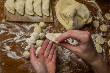 Bir kadın aşçı el un hamur bir tablo üzerinde pişmiş ve vareniki yapmak