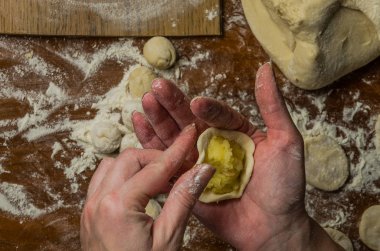 Bir kadın aşçı el un hamur bir tablo üzerinde pişmiş ve vareniki yapmak