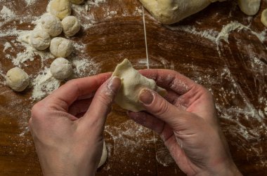 Bir kadın aşçı el un hamur bir tablo üzerinde pişmiş ve vareniki yapmak
