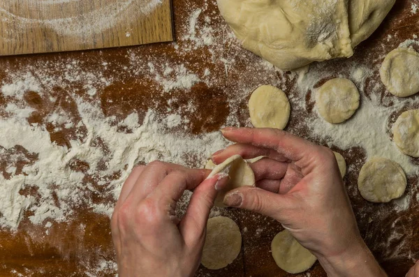 Bir kadın aşçı el un hamur bir tablo üzerinde pişmiş ve vareniki yapmak