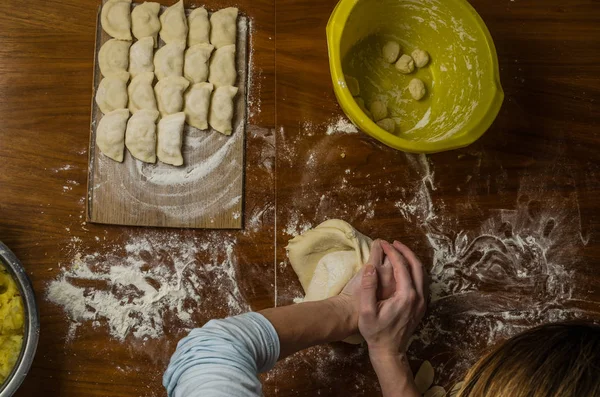 Bir kadın aşçı el un hamur bir tablo üzerinde pişmiş ve vareniki yapmak