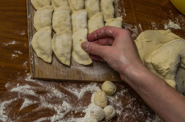 Bir kadın aşçı el un hamur bir tablo üzerinde pişmiş ve vareniki yapmak