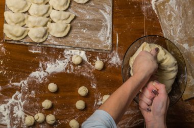Bir kadın aşçı el un hamur bir tablo üzerinde pişmiş ve vareniki yapmak
