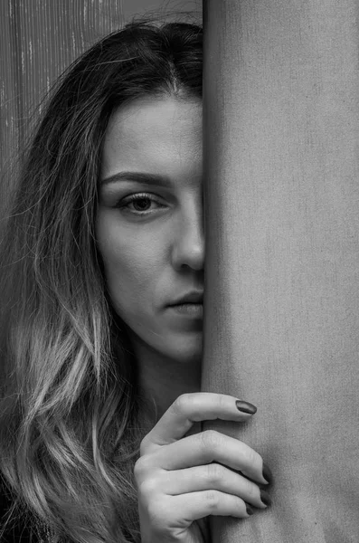 Bir perdenin arkasında gizli bir genç sevimli kızın yarım yüz