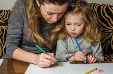 Genç güzel anne kızıyla birlikte çizmek ile renkli kalemler kağıt üzerinde mutlu bir aile