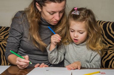 Genç güzel anne kızıyla birlikte çizmek ile renkli kalemler kağıt üzerinde mutlu bir aile