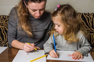 Genç güzel anne kızıyla birlikte çizmek ile renkli kalemler kağıt üzerinde mutlu bir aile