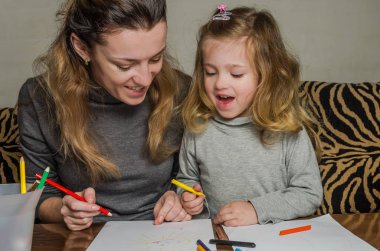 Genç güzel anne kızıyla birlikte çizmek ile renkli kalemler kağıt üzerinde mutlu bir aile