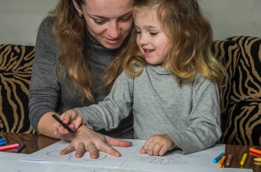 Genç güzel anne kızıyla birlikte çizmek ile renkli kalemler kağıt üzerinde mutlu bir aile