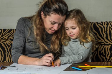 Genç güzel anne kızıyla birlikte çizmek ile renkli kalemler kağıt üzerinde mutlu bir aile