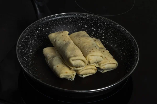 Pancakes stuffed in a frying pan on an induction cooker