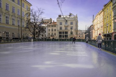 Lviv, Ukrayna - Şubat 2018: Buz buz pateni pisti ile güneşli bir öğleden sonra patenciler Merkezi Lviv, Ukrayna