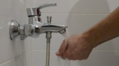 Bir adam temiz suyla musluk altında sabunla ellerini yıkar