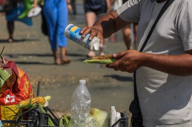 Roma, İtalya - Temmuz 2019: Izgara mısır satıcısı plajda tuzladı