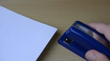 Ofis zımbası kağıt yapraklarını zımbalıyor.