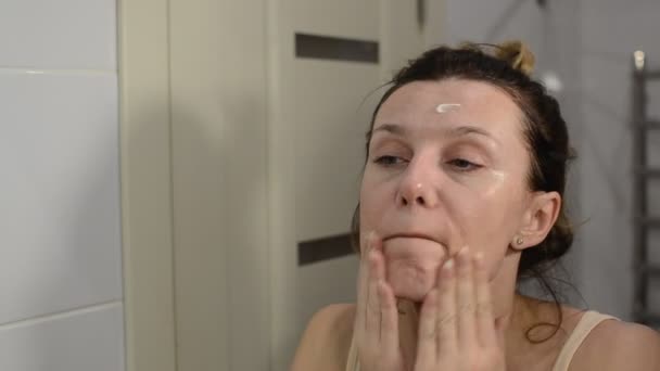 Junges Schönes Mädchen Cremt Sich Badezimmer Unter Den Augen Ein — Stockvideo