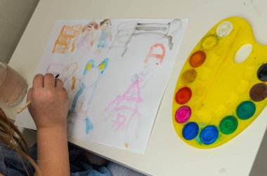 Küçük kız suluboya resimler çiziyor