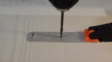 Usta bir matkapla metal bir plaka deliyor.