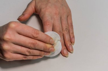 Kadın eski tırnak cilasını pamukla temizliyor, manikür yapıyor.