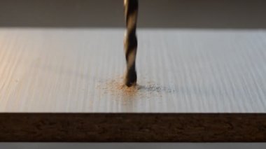 Usta bir matkapla yonga tahtasından ahşap bir tabak deliyor.