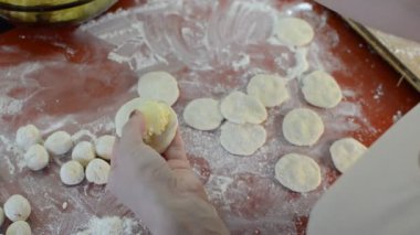 Kadın aşçı un hamurundan köfte ve patates heykeli yapıyor.