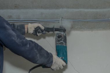 İşçi beton bir duvarı çekiçle deliyor.