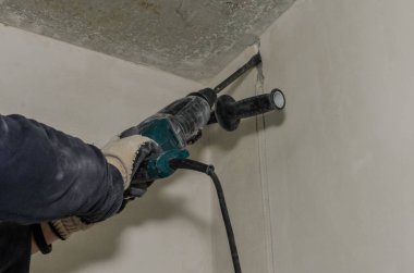 İşçi, bir delgi keskisiyle beton duvarı yıkıyor.