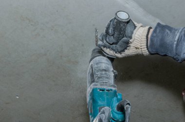 İşçi beton bir duvarı çekiçle deliyor.