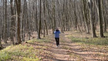 Maskeli genç kız ormanda koşuyor.