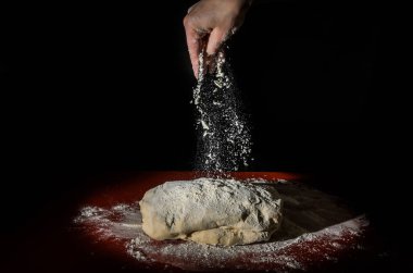 Şef, siyah arka planda beyaz un serpiştiriyor.