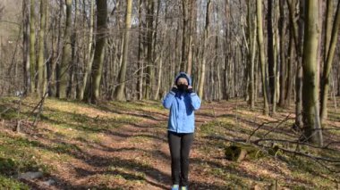 Maskeli genç kız ormanda koşuyor.