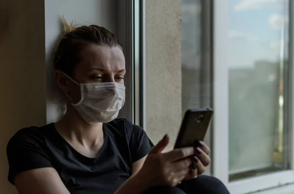 Young Girl Medical Mask Sits Windowsill Window Looks Smartphone — Stock Photo, Image