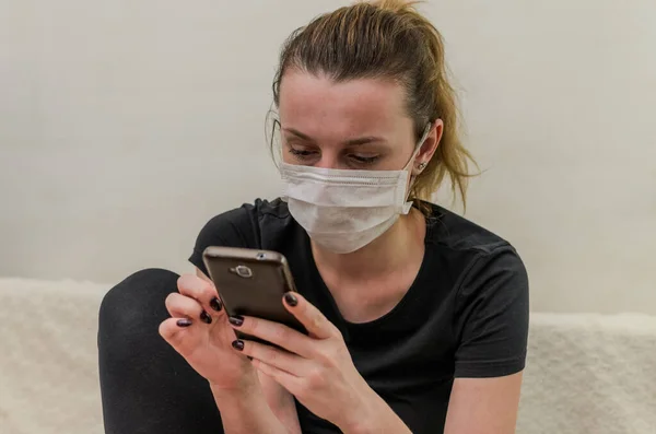 Ένα Νεαρό Κορίτσι Ιατρική Μάσκα Πληκτρολογεί Ένα Μήνυμα Ένα Smartphone — Φωτογραφία Αρχείου