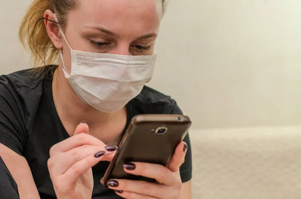 Egy Fiatal Lány Orvosi Maszkban Üzenetet Gépel Egy Okostelefonon — Stock Fotó
